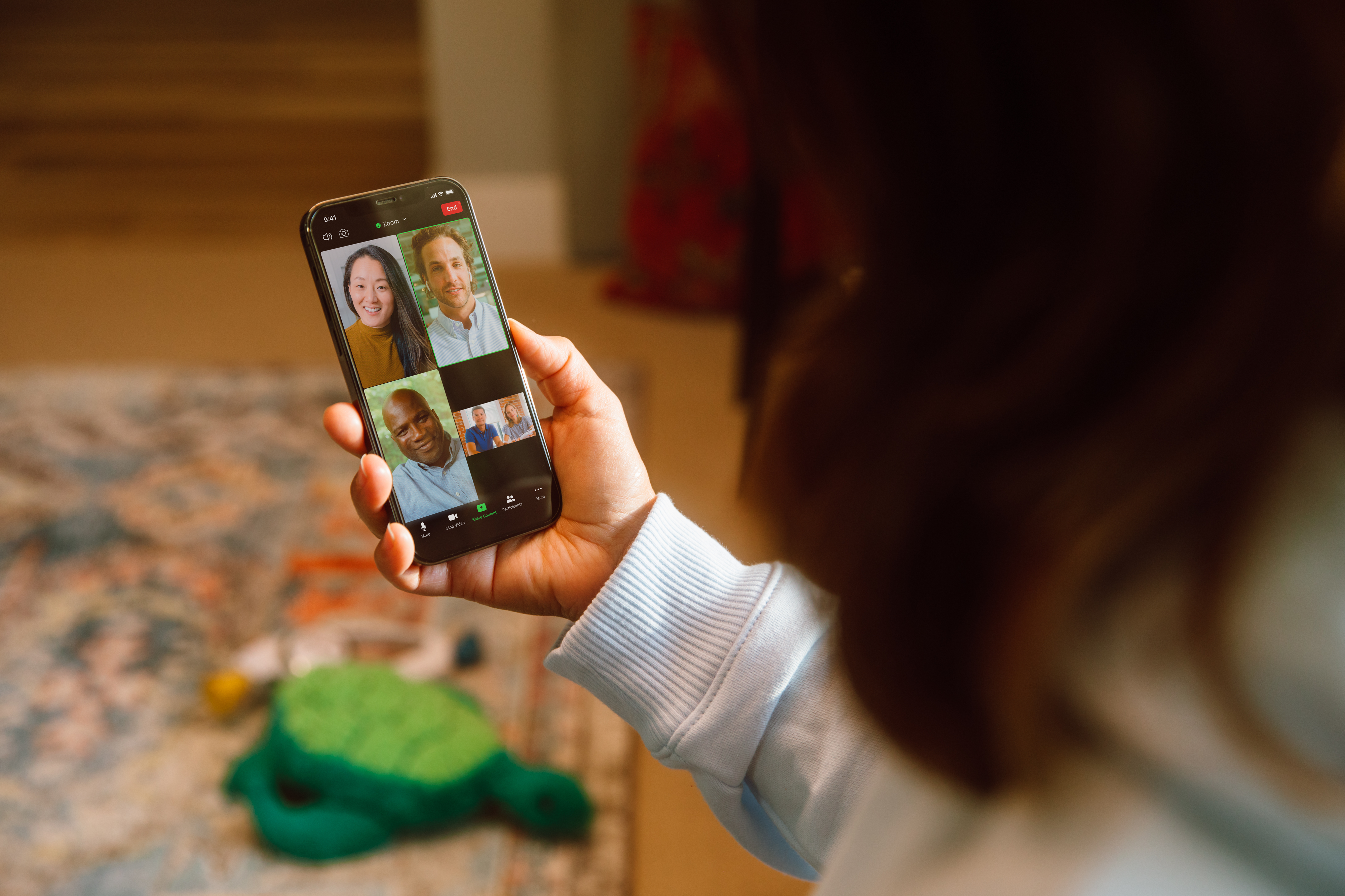 Zoom Phone. An individual holding a mobile phone attending a mobile video conference call 
