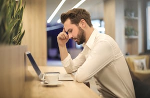 man-with-hand-on-temple-looking-at-laptop-842554