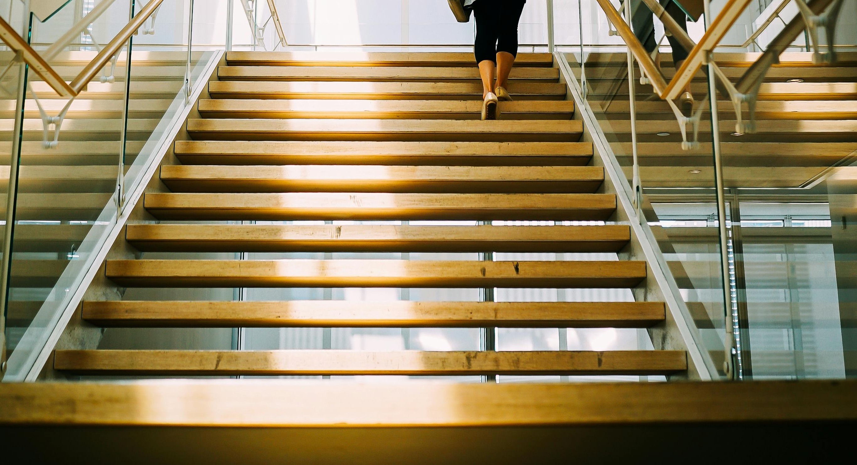 AI-Enhanced Unified Communications. An individual ascending a staircase, with a focus on the act of walking up steps.