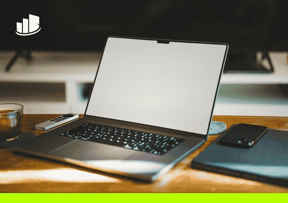 A modern remote workspace featuring an open laptop with a blank screen, a smartphone, a tablet, and a cup of coffee on a wooden desk, symbolizing mobile UCaaS and remote work flexibility.