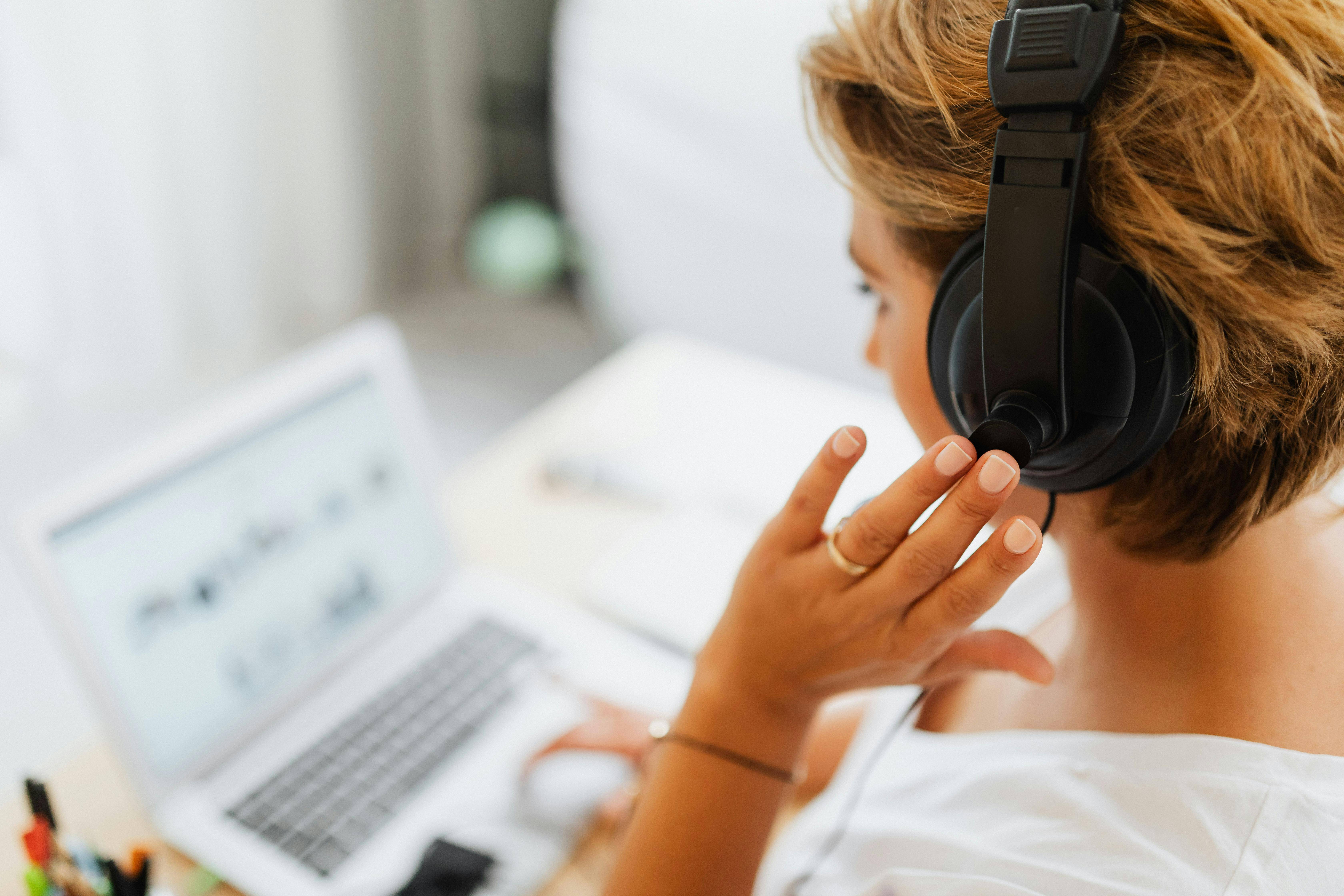 CT Cloud Contact Center. A woman in headphones is at her desk, working intently on her laptop, embodying a dedicated workspace atmosphere.