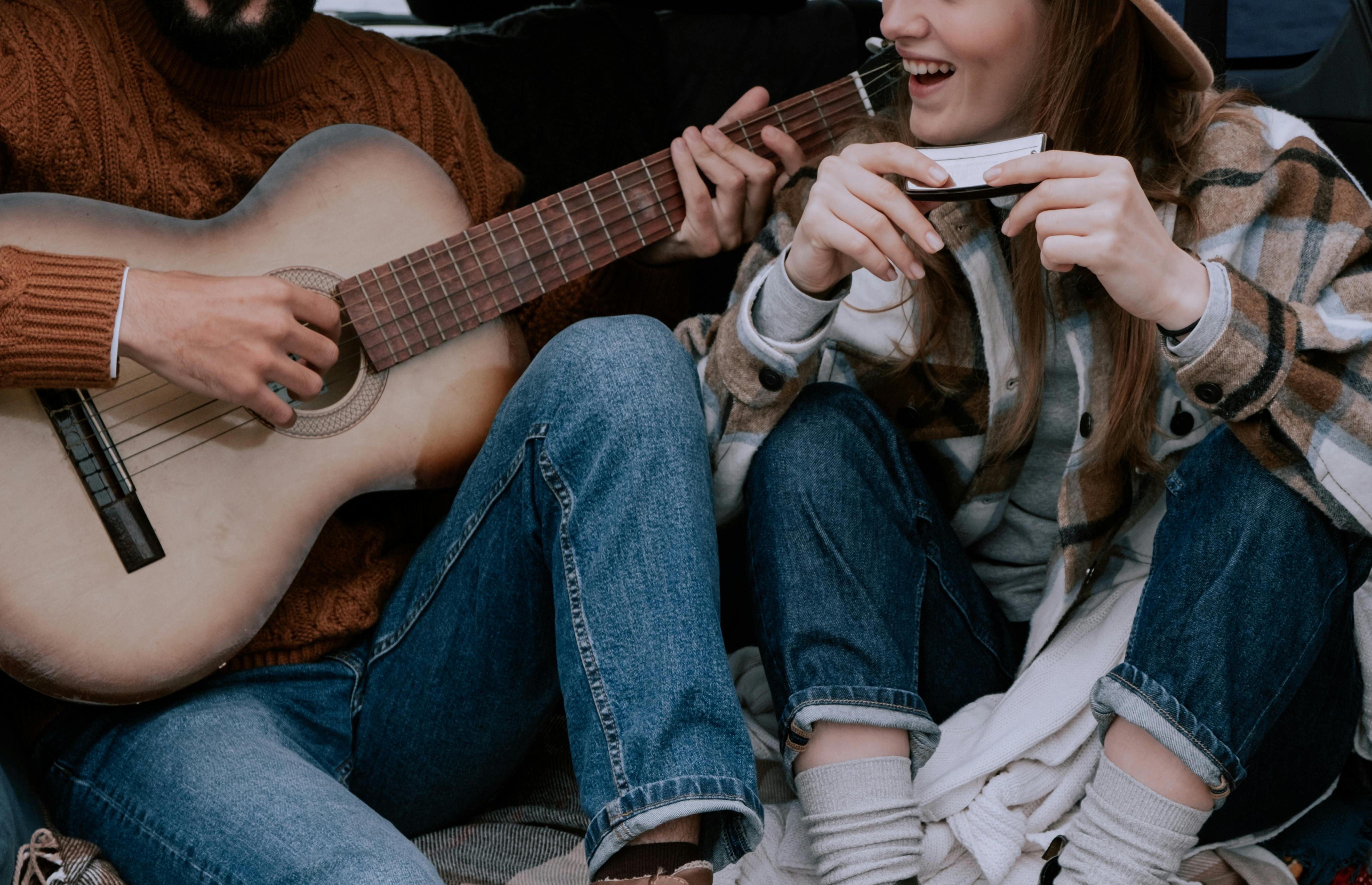 UC Solutions. A person and person sitting in a car playing guitar.