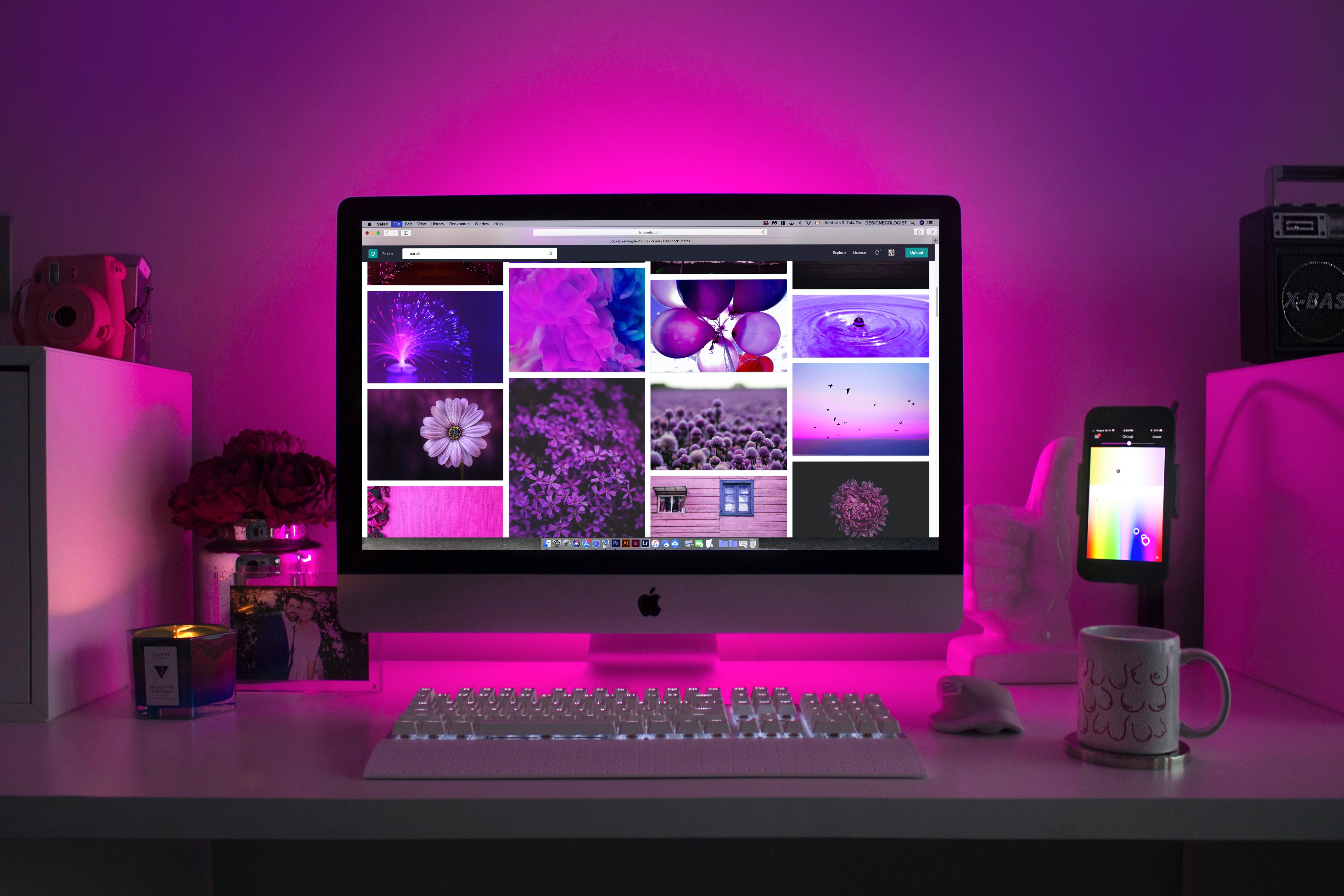Apple Desktop computer and keyboard on top of a desk with purple LED lights illuminating the room