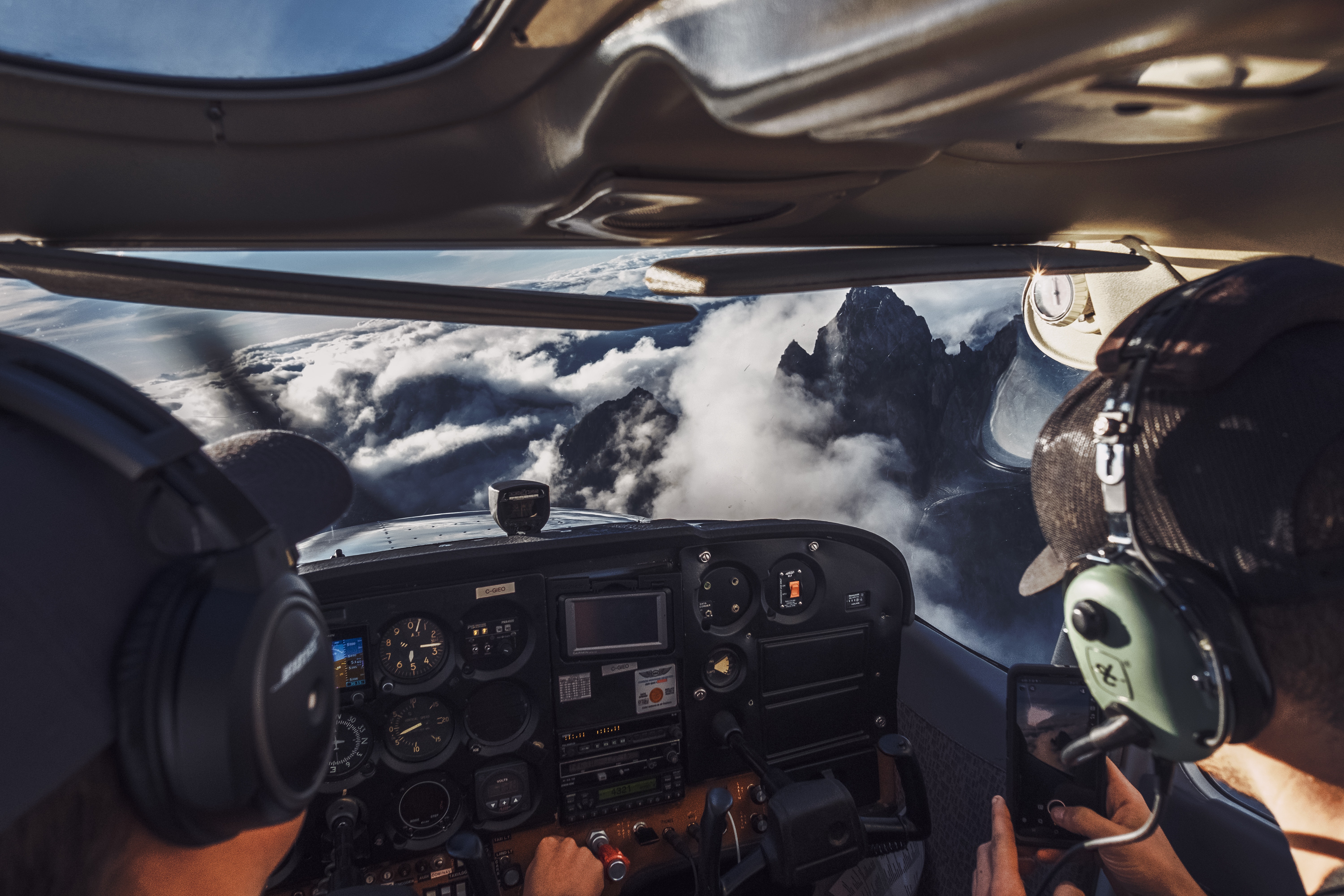 a cockpit of a plane with clouds and mountains in the background