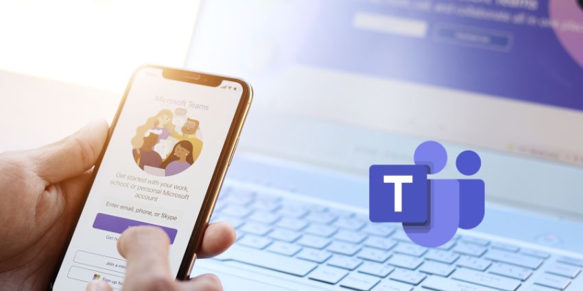 Someone using Microsoft Teams on their phone with a laptop in the background 